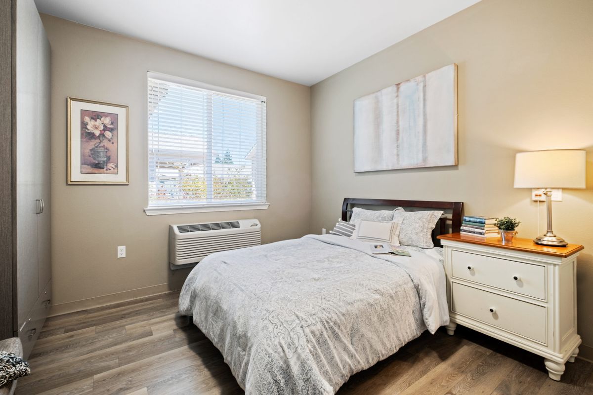 A cozy bedroom with a neatly made bed, nightstand, and wall art.