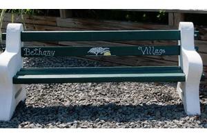 A wooden park bench with an engraving of a mountain scene and text.