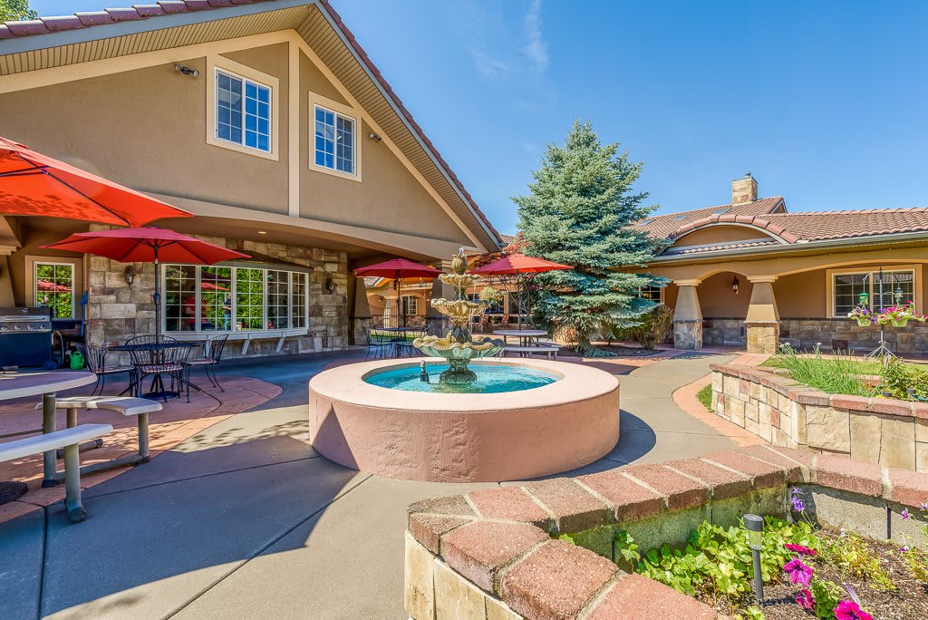 A beautiful patio with a fountain and outdoor seating, surrounded by lush greenery.