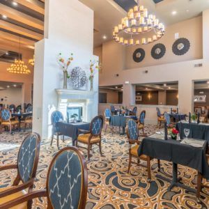 An elegant restaurant interior with chandeliers, a fireplace, and stylish seating.