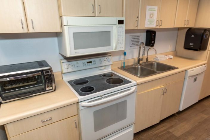 A modern kitchen setup featuring an oven with a built-in stovetop, a microwave above the counter, and a sink.