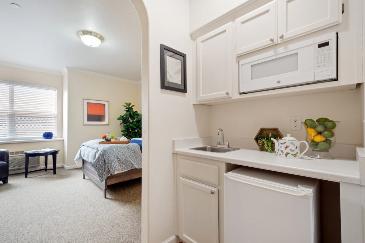 A cozy studio apartment featuring a bedroom and a compact kitchenette with minimalist decor.