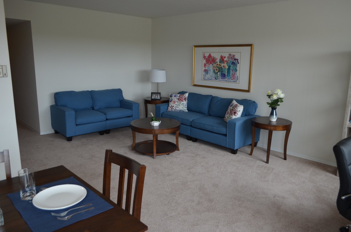 A cozy living room with blue sofas and a dining area.