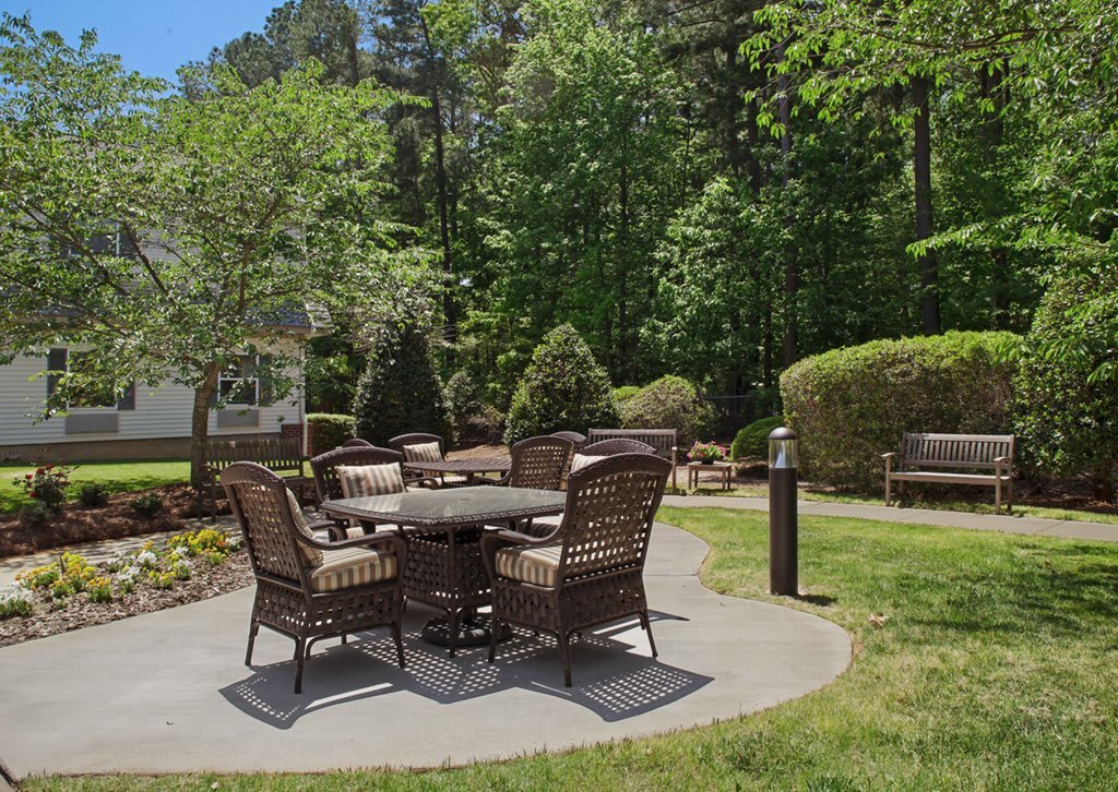 A serene garden patio with wicker furniture surrounded by greenery.