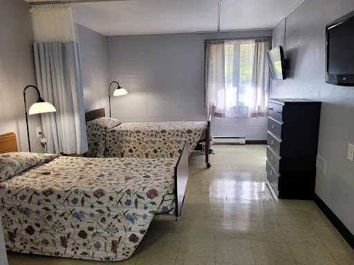 A cozy hotel room featuring two neatly made beds, a dresser, and a large window letting in natural light.