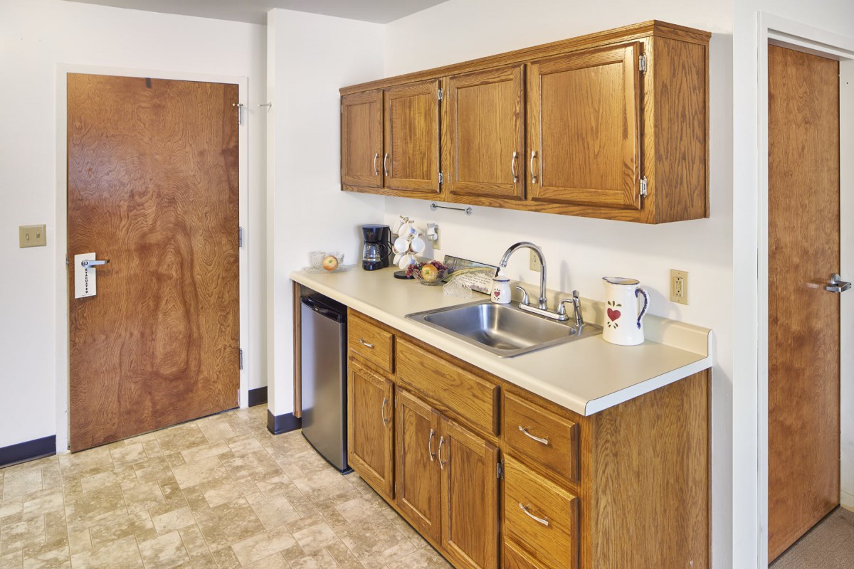 A simple kitchen with wooden cabinets and basic appliances.