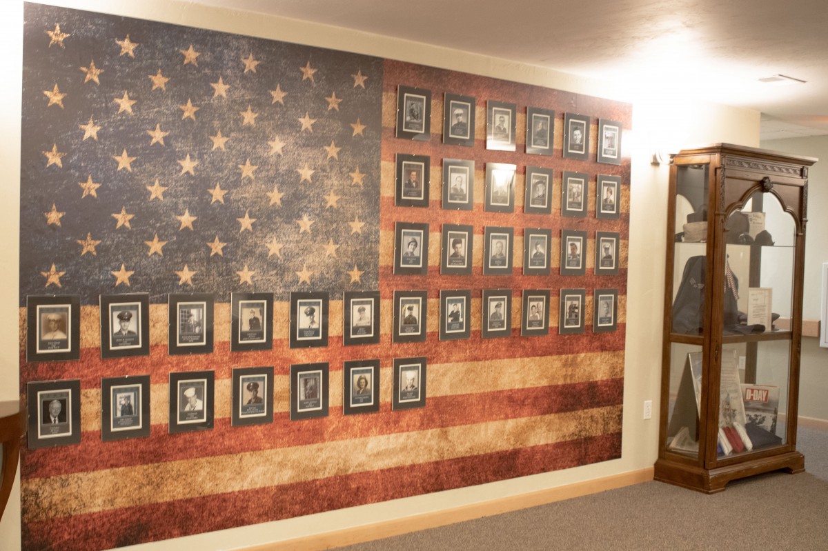 A wall adorned with an American flag design featuring numerous framed photographs.