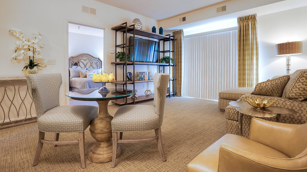 A cozy living room with a dining table, comfortable seating, and a television on shelves.