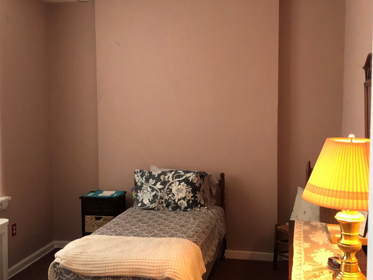 A cozy bedroom with a single bed, nightstand, and lamp.
