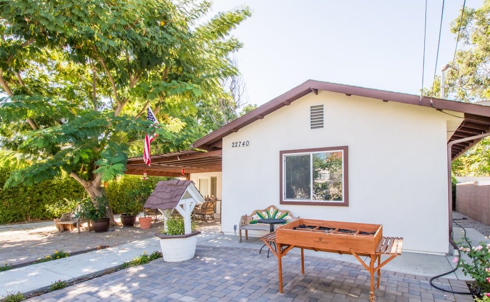 A cozy house with a charming garden and patio area, surrounded by lush greenery.