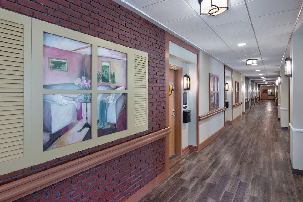 A well-decorated hallway with brick walls, decorative paintings, and wood flooring.