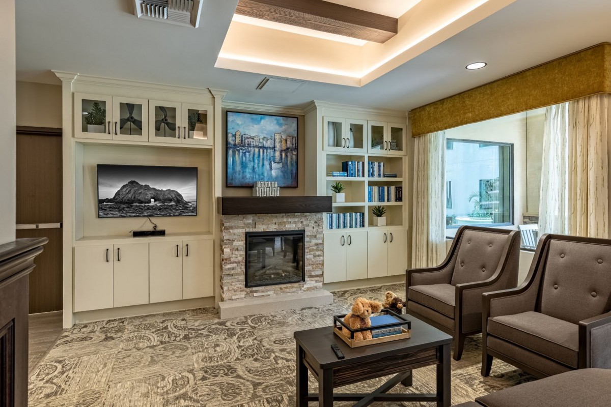 A cozy living room with a modern fireplace, surrounded by built-in shelves and comfortable seating.