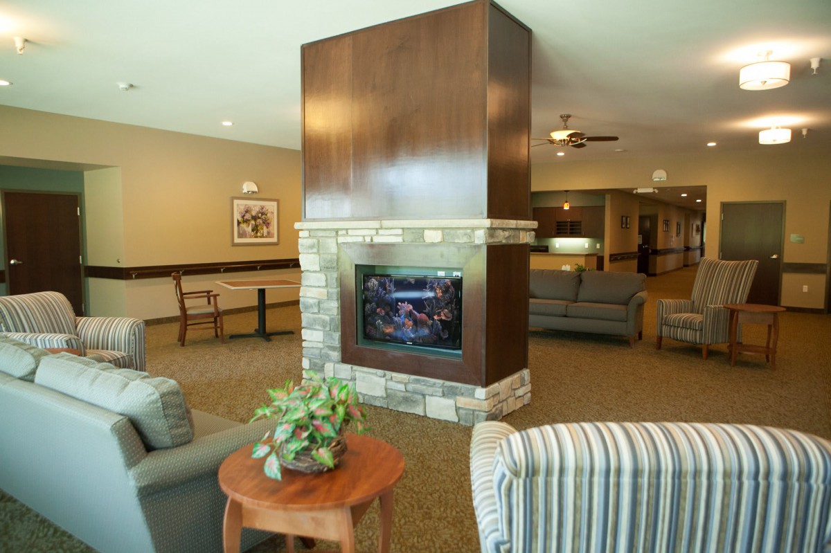 A cozy living room interior featuring a central fireplace surrounded by comfortable seating.