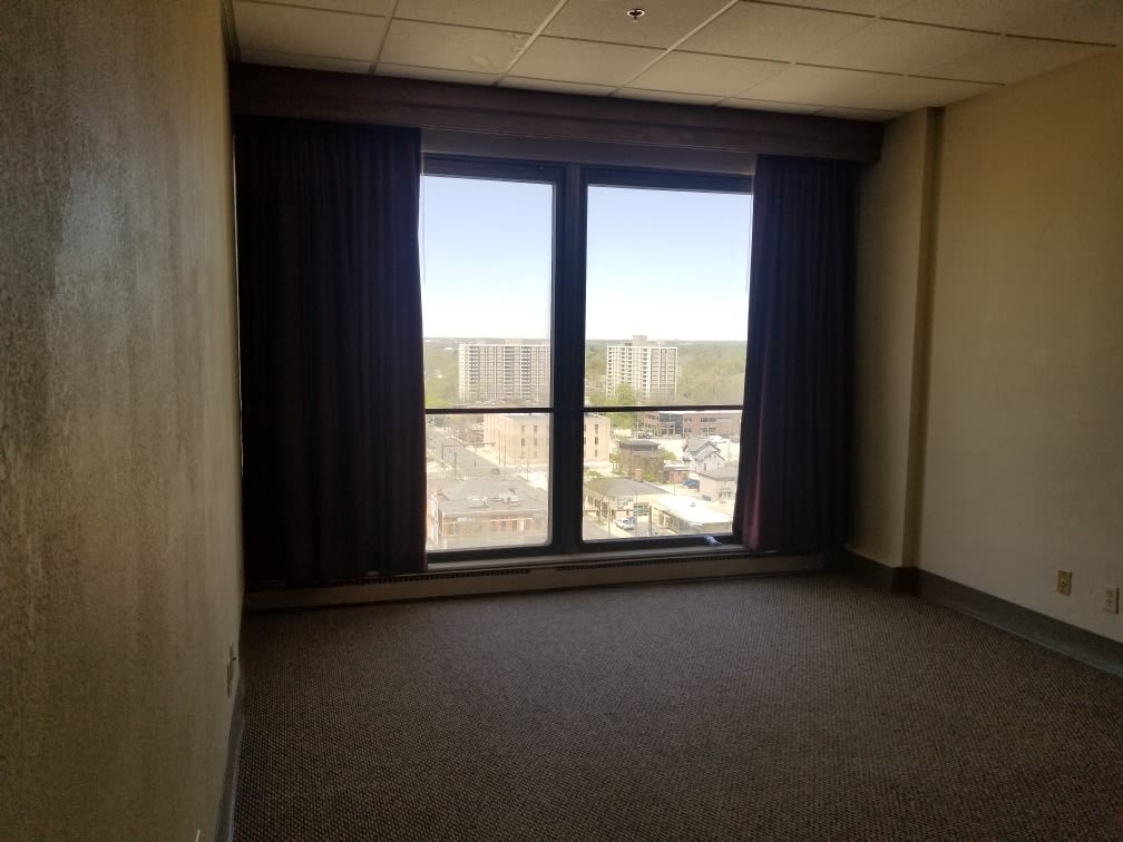 An empty room with large windows and curtains, overlooking a distant outdoor view.