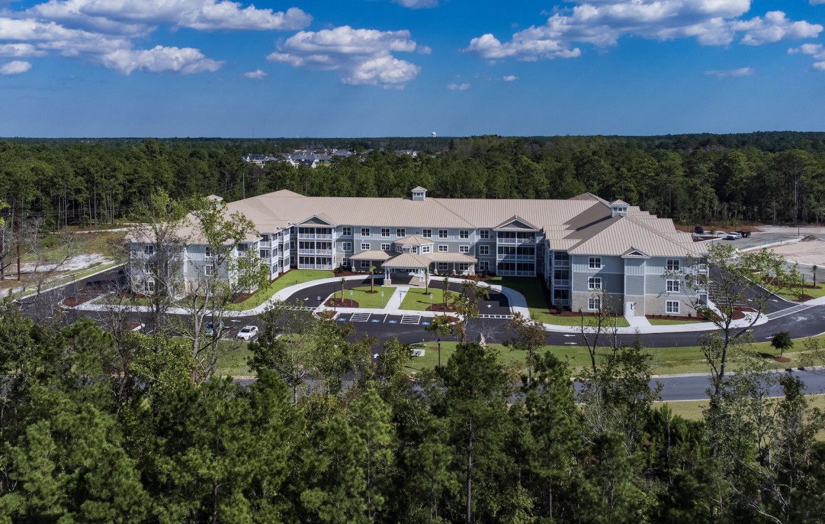 Aerial view of a large residential building surrounded by trees.