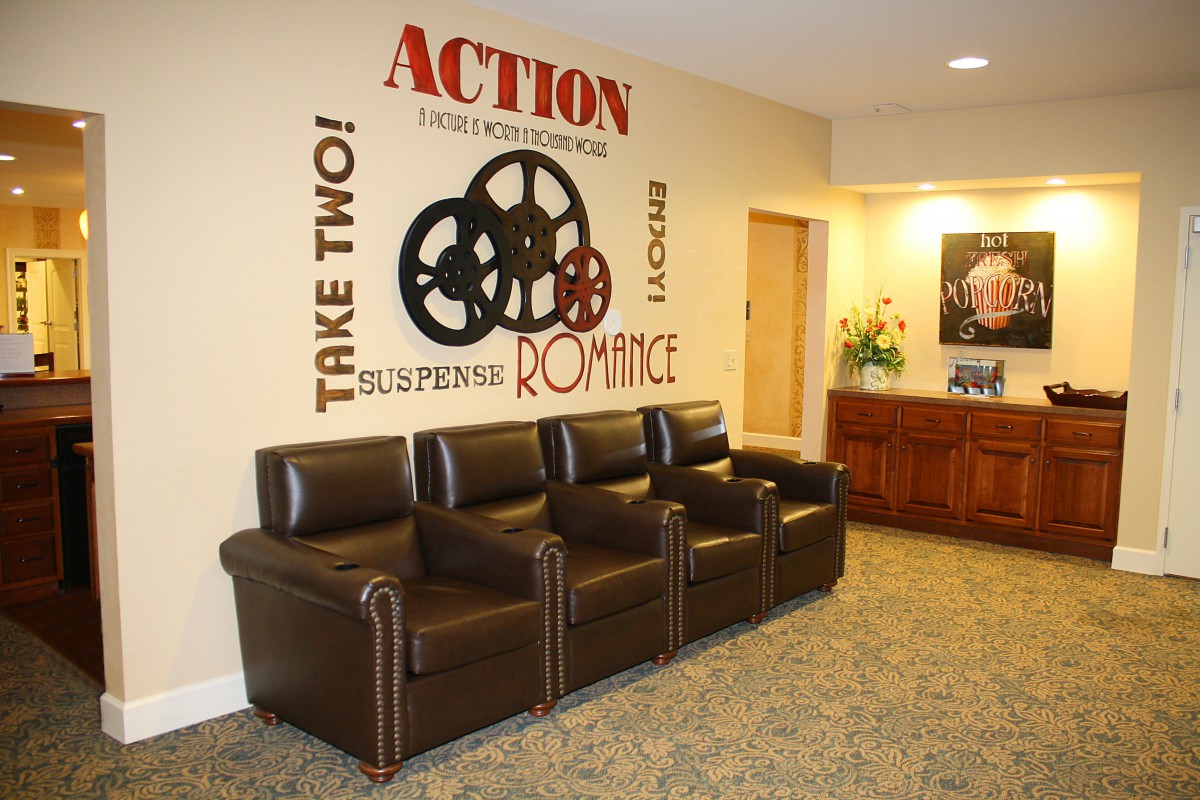 A cozy waiting area with leather chairs and movie-themed wall art featuring film reels.
