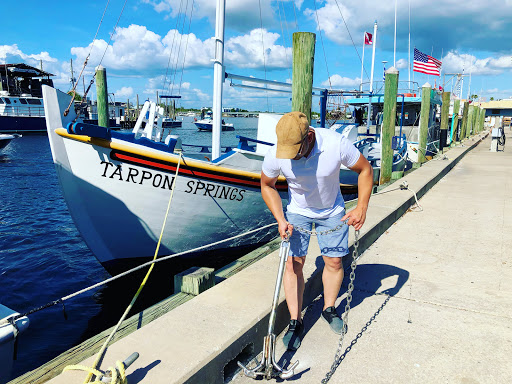 A person preparing for a fishing trip at the marina, with the boat 'Tarpon Springs' in the background.