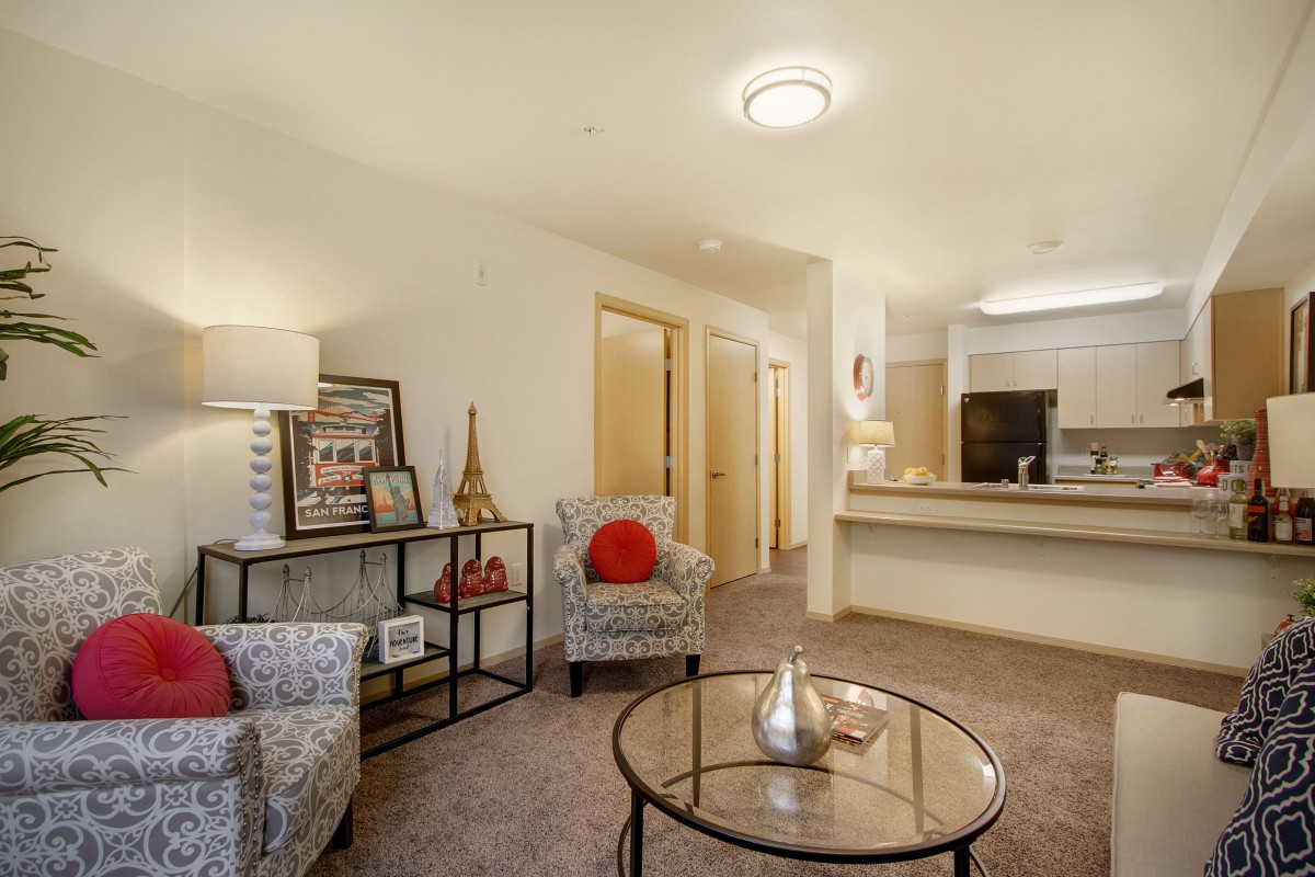 A cozy living room with stylish furniture and warm lighting, featuring a small table and decorative elements.