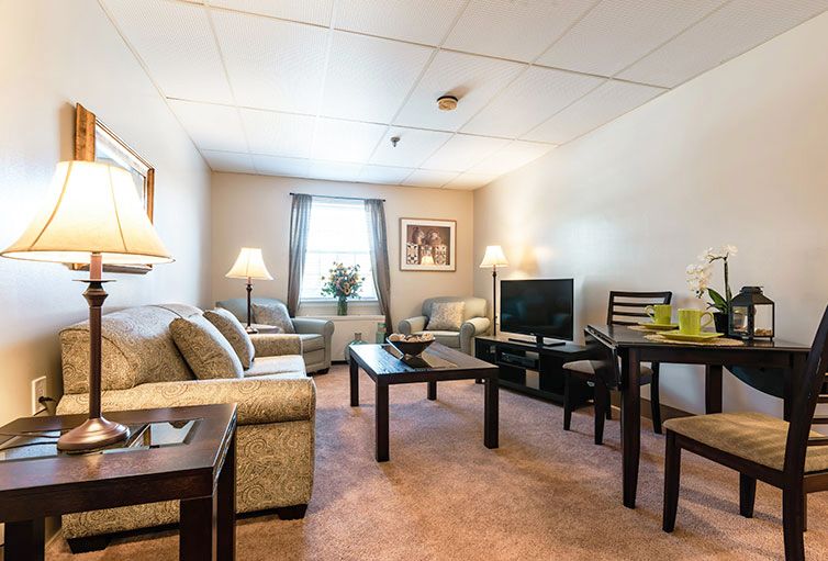 A cozy living room with a sofa, coffee table, TV, and dining area.