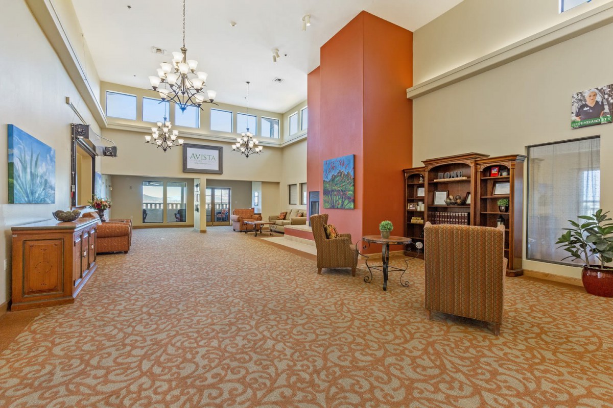 A spacious lobby with comfortable seating, chandeliers, and bookshelves.