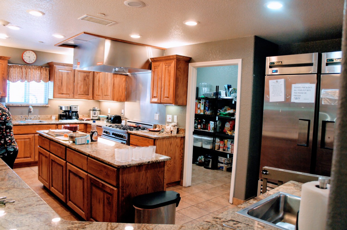 A modern kitchen with wooden cabinets, a central island, and stainless steel appliances.