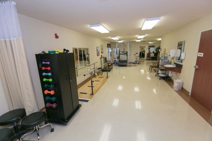 A spacious rehabilitation center equipped with exercise equipment and therapy stations.