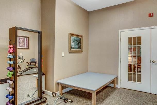 A small exercise room with a table, mirror, and artwork on the wall.