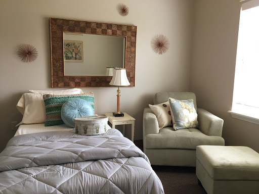 A cozy bedroom setup featuring a bed with decorative pillows, an armchair, and a stylish mirror.