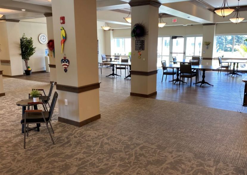 Spacious dining area with tables and chairs, featuring large windows.