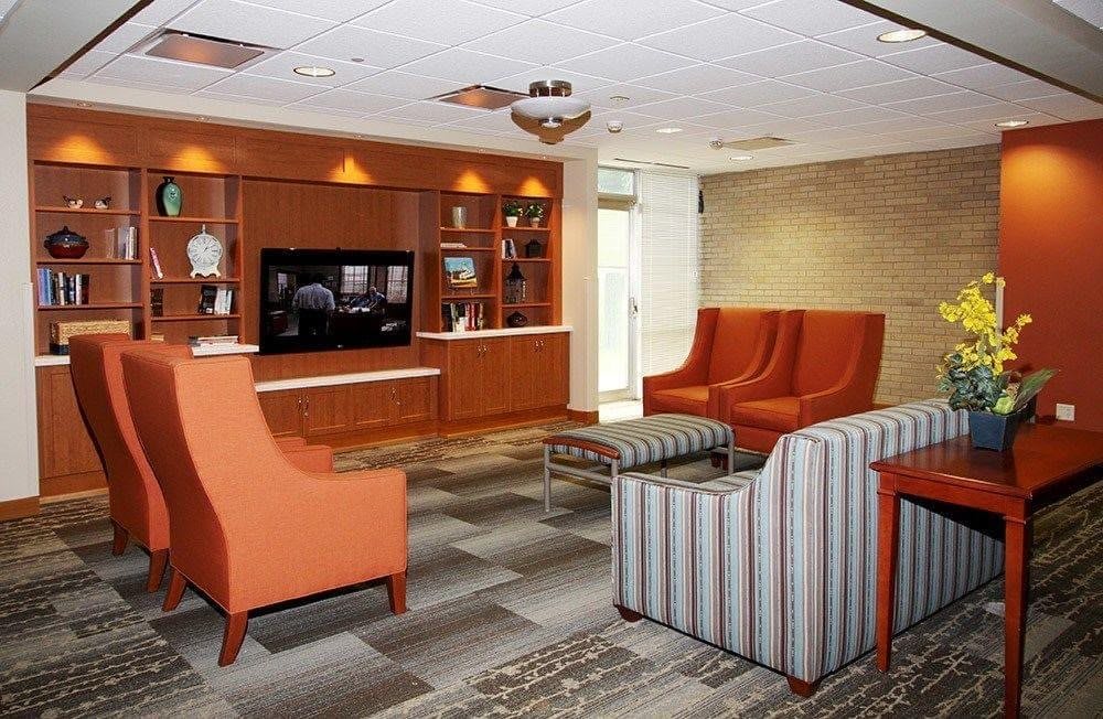 A modern lobby seating area with comfortable chairs and a television.