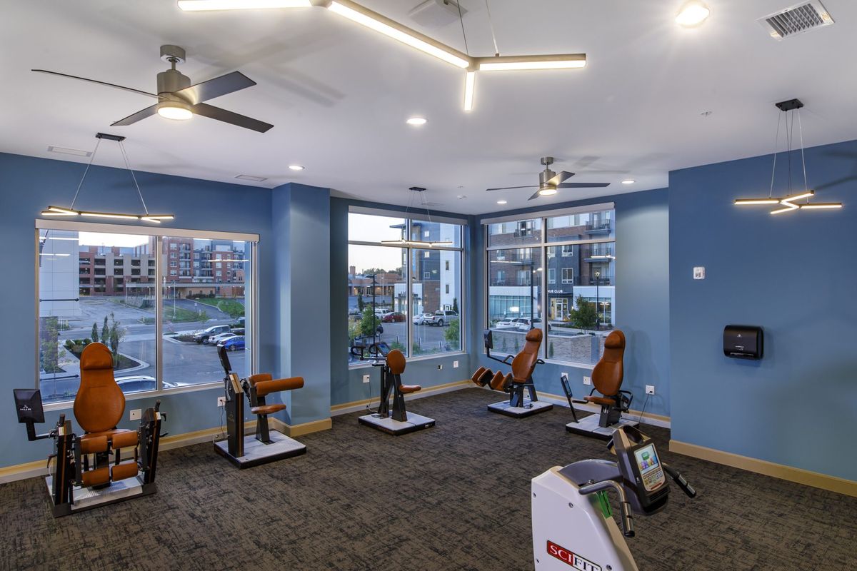 A modern gym with exercise machines and large windows.