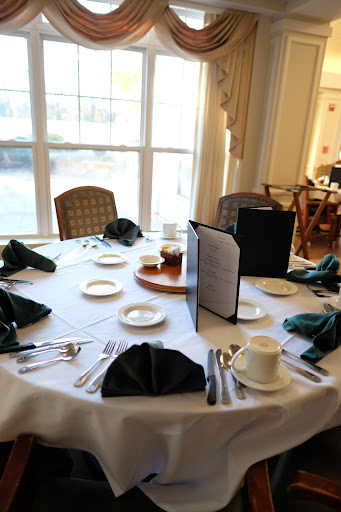 A beautifully arranged dining table with green napkins, plates, cutlery, and a menu in an elegant setting.