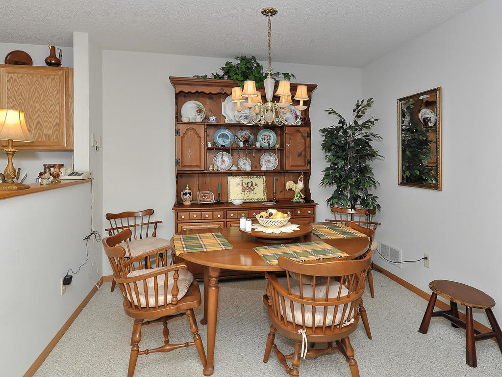 A cozy dining room with a wooden table, chairs, and a china cabinet displaying decorative plates.