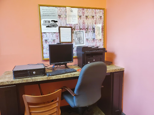 A cozy workspace featuring a computer, printer, and bulletin board.