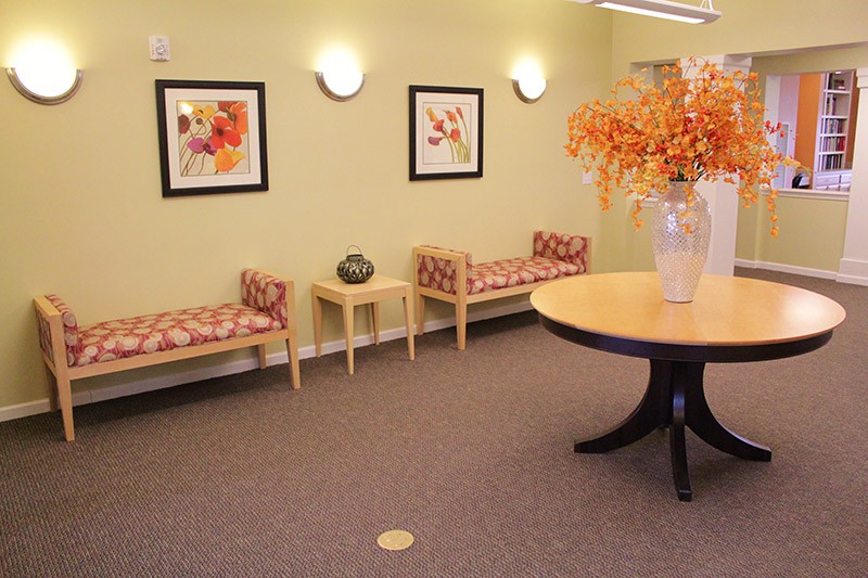 A cozy waiting room with benches, decorative artwork, and a table with a floral arrangement.