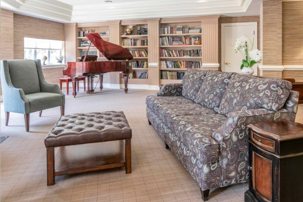 A cozy living room with a grand piano and bookshelves.