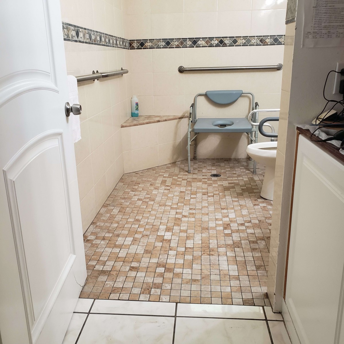 An accessible bathroom equipped with a shower chair and grab bars for support.