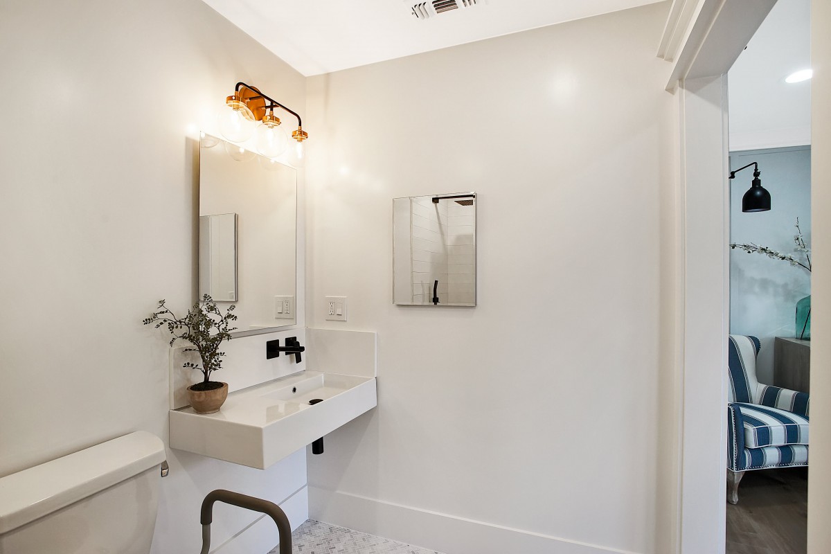 A minimalist bathroom with a wall-mounted sink, mirror, and modern lighting.