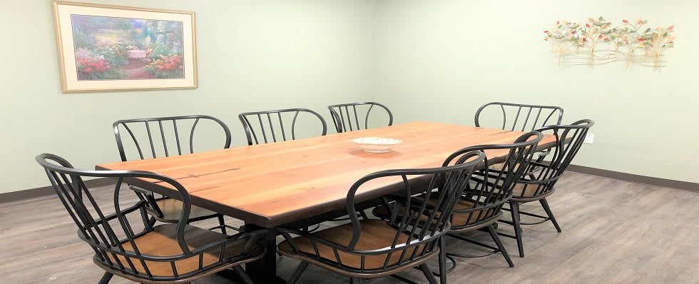 A conference room with a wooden table and black chairs.