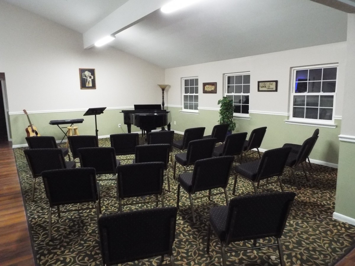 A small music room with rows of chairs facing a grand piano.