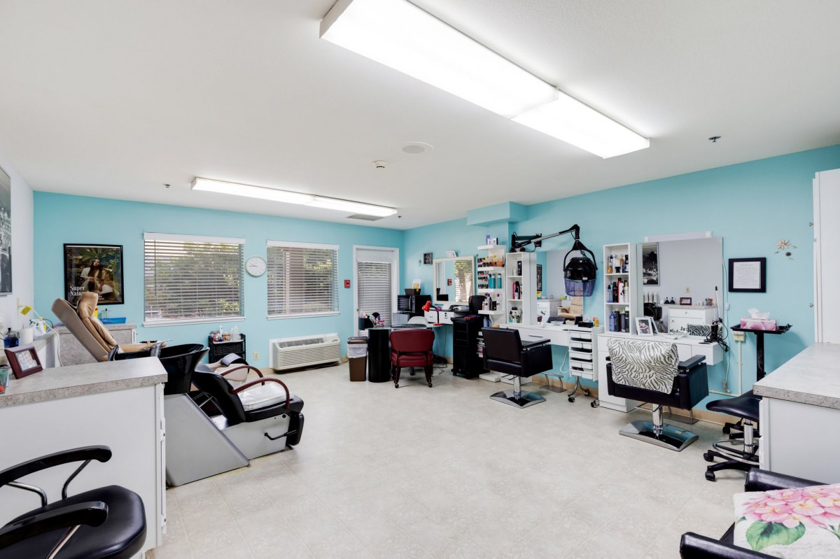 A spacious hair salon with turquoise walls, mirrors, and styling chairs under bright lighting.