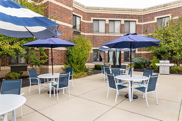 A well-maintained patio with tables, chairs, and umbrellas outside a brick building.