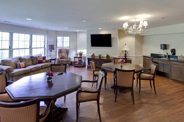 A spacious living room with elegant furniture, tables, chairs, and a flat-screen television.