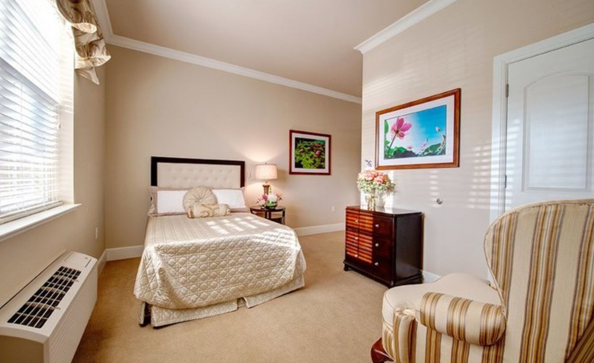 A cozy bedroom featuring elegant decor with a bed, nightstand, and artwork on the walls.