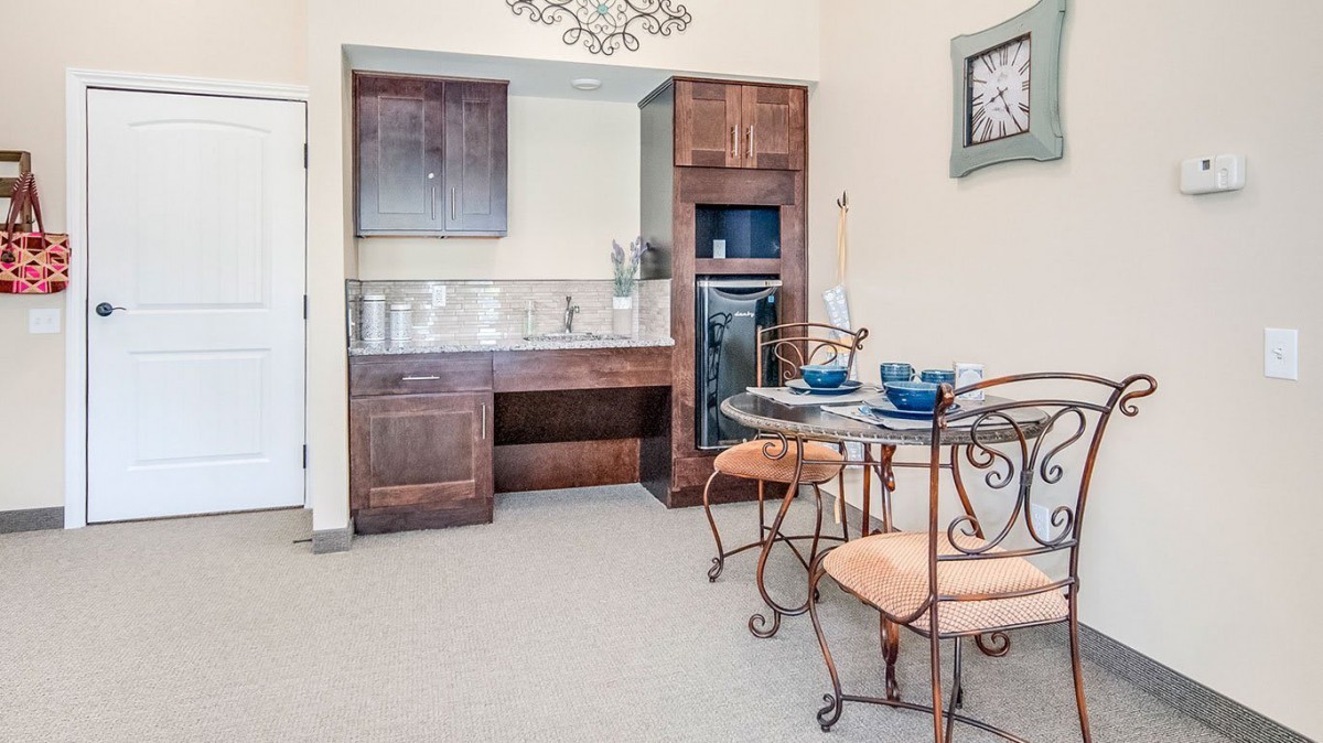 A cozy kitchen and dining area featuring wooden cabinets, a small table with chairs, and elegant decor.