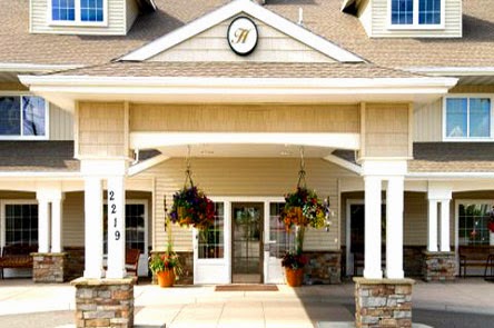 A welcoming entrance adorned with vibrant flowers and a classic clock.