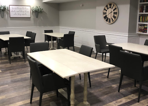 A modern dining area featuring simple tables and dark chairs, highlighted by a clock on the wall.