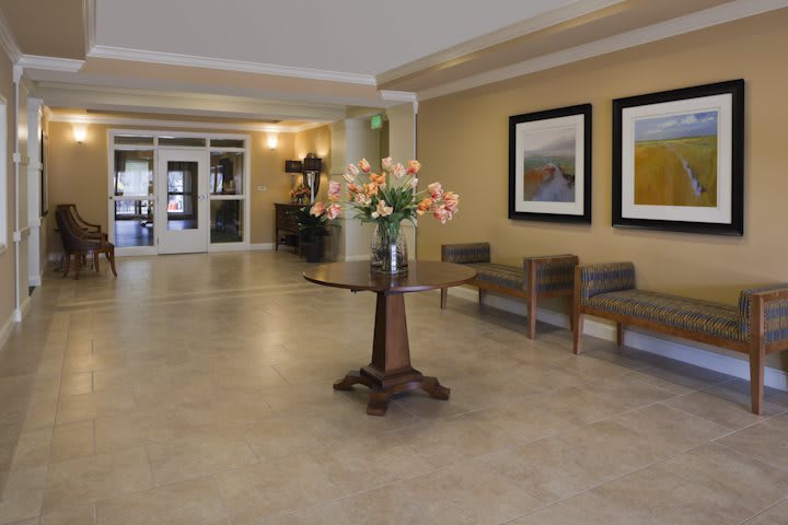 A modern lobby with a central table displaying flowers, surrounded by artwork and seating.