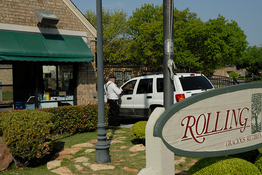 A white vehicle parked near a storefront with a green awning and sign.