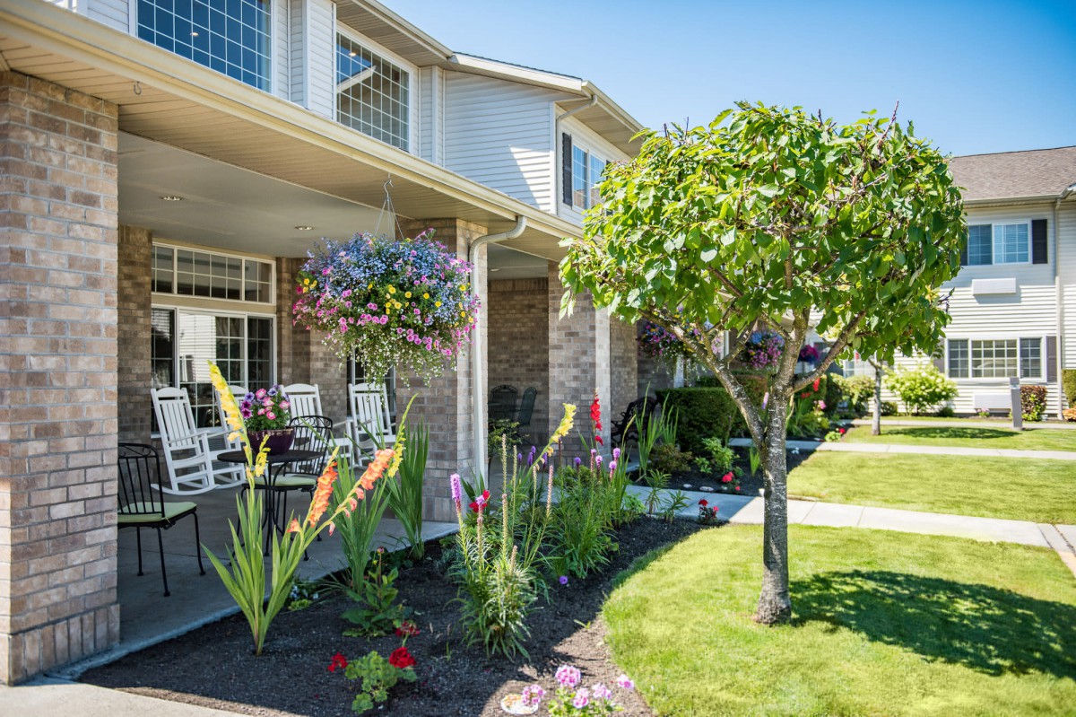 A beautiful suburban house with a well-maintained garden and porch under a clear blue sky.
